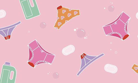 Colourful underwear stained with period blood, surrounded by soap bars, bubbles and detergent bottles.