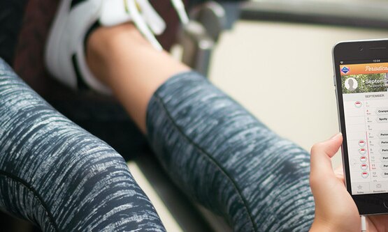 Woman using periodical app to calculate ovulation while wearing gym leggings and trainers