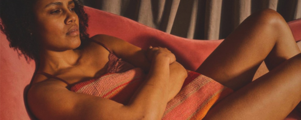 Et billede af en ung kvinde med menstruationssmerter, der holder en pude.