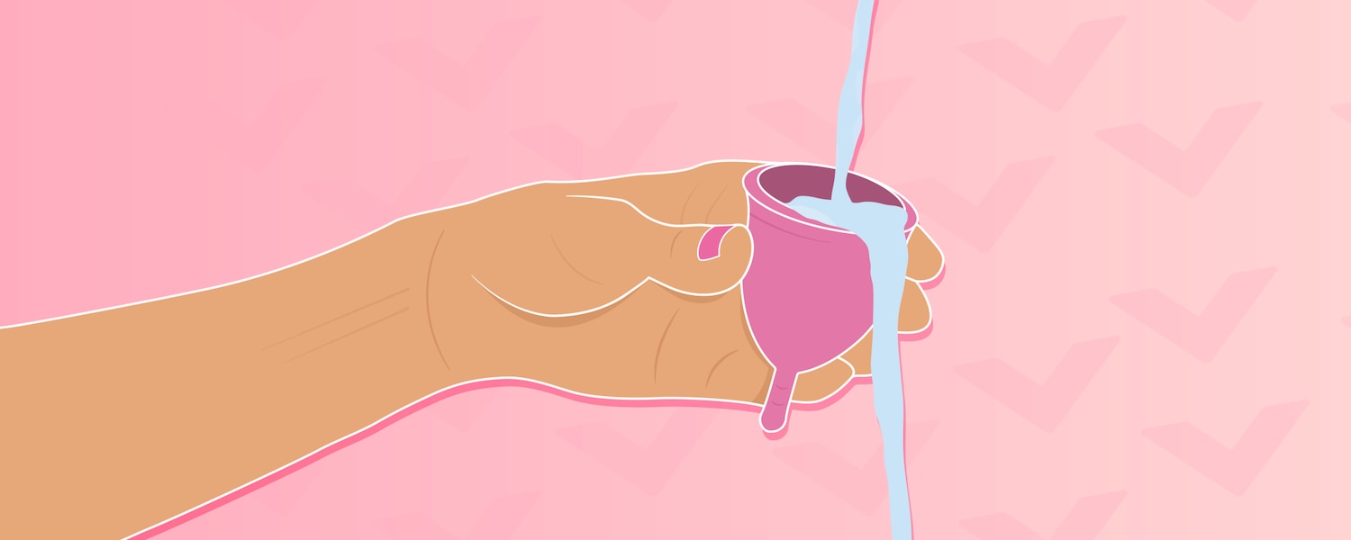 Gros plan d'un bras rinçant une coupe menstruelle avec de l'eau.