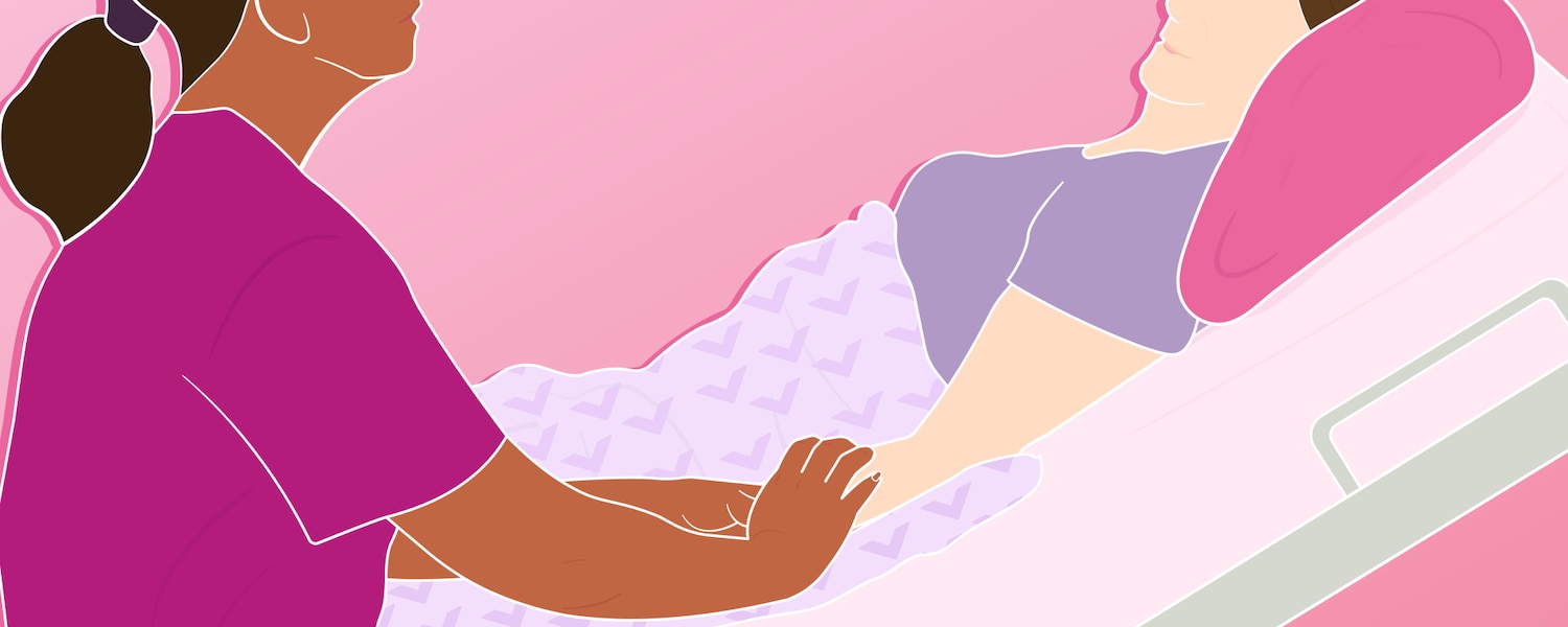 A patient lying down in a hospital bed with their loved one at their side holding their hand.
