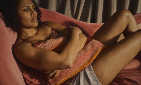 Woman holding pillow against her tummy as she can’t sleep because of period cramps.