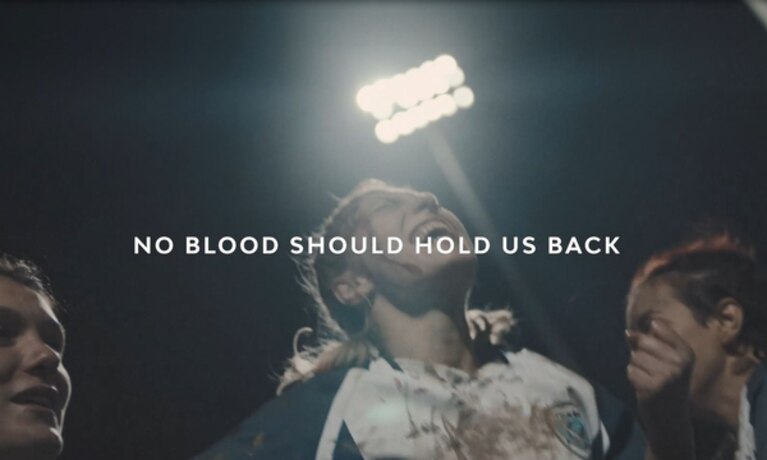 Women playing football with text overlay "No blood should hold us back"