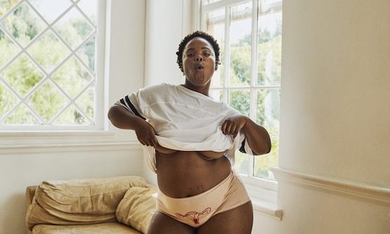 Donna con slip con su ricamato l’apparato riproduttivo femminile mostra smagliature post parto.