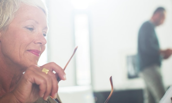 A mature woman reading a magazine with glasses in her hand - Libresse