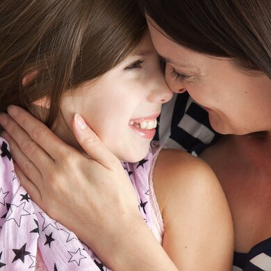 Imagen de una madre y su hija en el sofá abrazadas y sonriendo - Saba