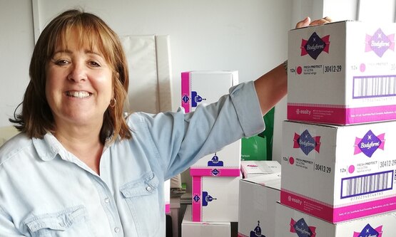 Woman in front of boxes of Bodyform sanitary products