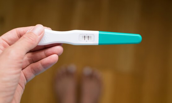 Hand holding positive pregnancy test